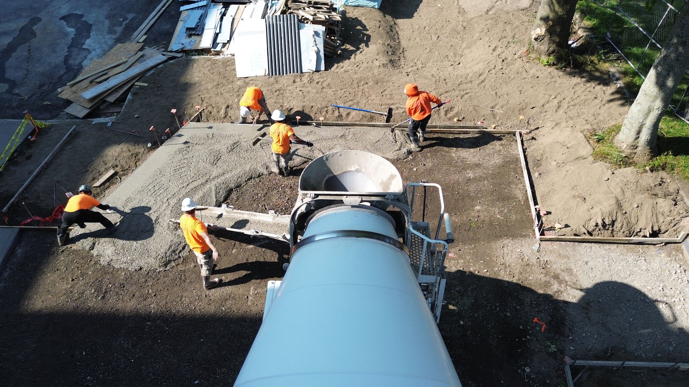 Aerial view of a crew screeding a fresh concrete pour as the mixer truck discharges